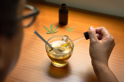 Close-up of hand holding drink on table