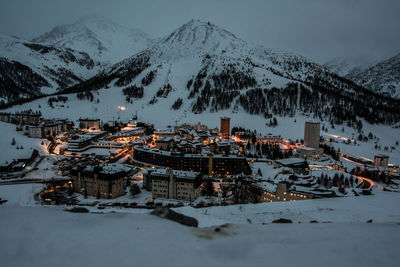 Panoramic view of houses and snowcapped mountains against sky