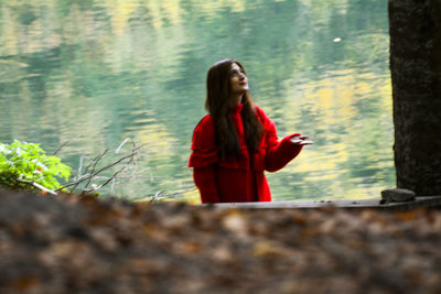 Young woman standing by red tree