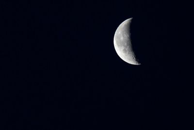 Low angle view of half moon against clear sky at night