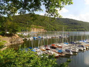 Boats moored in harbor at lake against sky