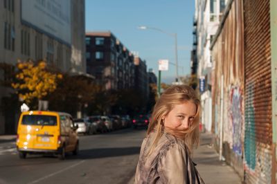 Young woman standing on road in city