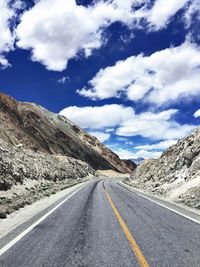 Road amidst mountains against cloudy sky