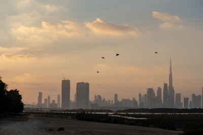 Buildings in city against sky during sunset