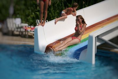 Full length of young woman wearing bikini enjoying on slide at water park