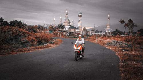 Man riding motorcycle on road against sky