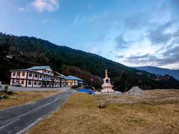 Scenic view of building by mountains against sky