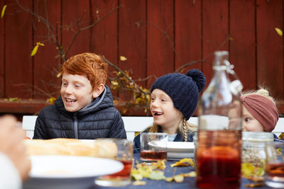 Happy male and female siblings sitting at table for meal