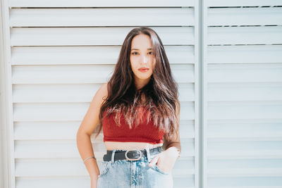 Portrait of young woman standing against wall