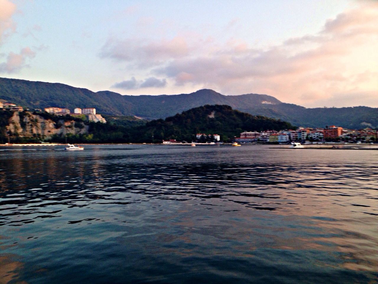 mountain, water, mountain range, sky, building exterior, waterfront, built structure, architecture, cloud - sky, lake, scenics, cloud, sea, tranquil scene, river, tranquility, rippled, house, beauty in nature, nature