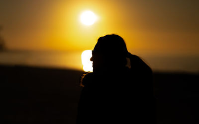 Silhouette woman standing against sky during sunset