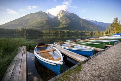 Boats moored at lakeshore against sky