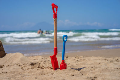 Shovels on beach against sky