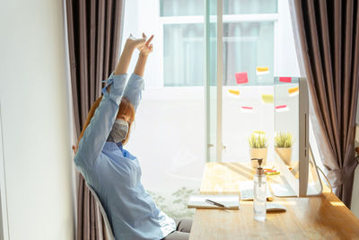 Side view of man sitting on table at home