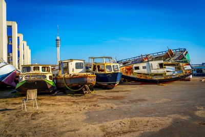 Boats moored on beach against clear blue sky