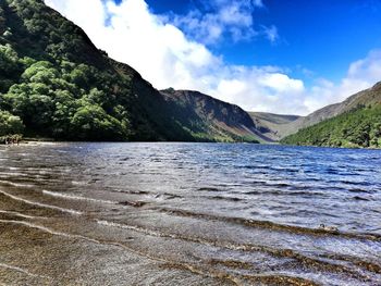 Scenic view of river by mountains against sky