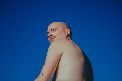 Portrait of shirtless man against clear blue sky