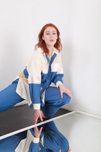 Fashion portrait of stylish woman in summer blue white stripes suit  sitting near reflecting mirror