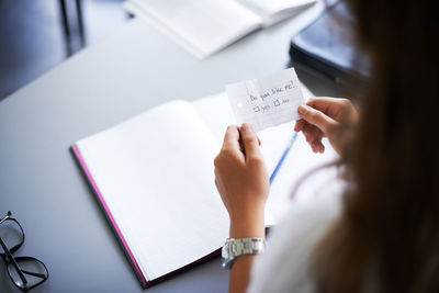 Midsection of doctor writing in book