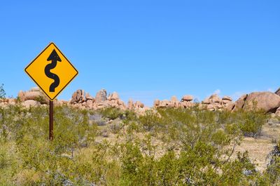 Warning sign on landscape against clear blue sky