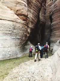 Rear view of people entering rock formation