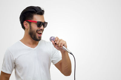 Young man holding microphone against white background