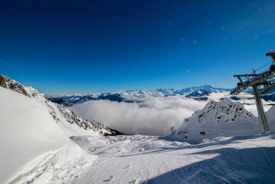 Scenic view of snow covered mountain against blue sky