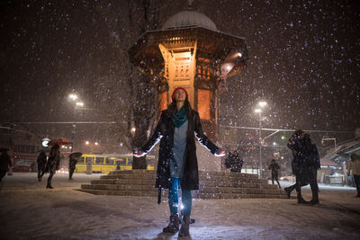 Woman standing on road against sky during snowfall
