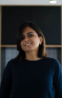 Portrait of smiling woman standing against wall