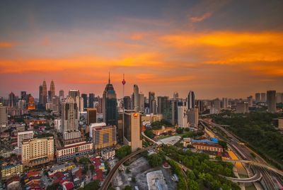 Aerial view of cityscape against cloudy sky during sunset