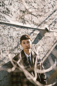 Portrait of young man standing against wall