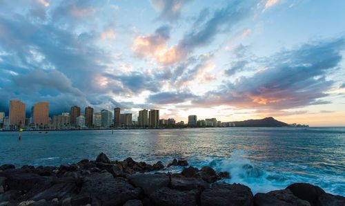 Scenic view of sea against cloudy sky during sunset