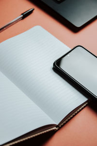 Close-up of mobile phone with diary on colored background