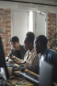 Female entrepreneur discussing with male colleague over computer in office