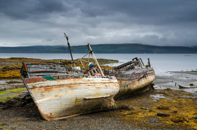 Abandoned boat moored on beach against sky