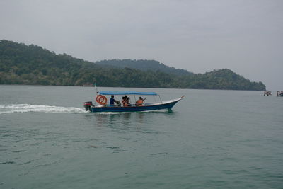 People in boat on sea against sky