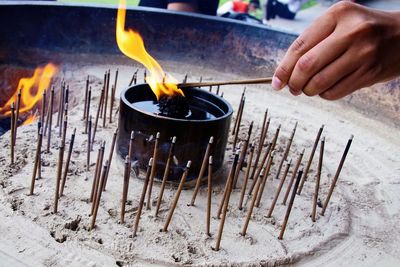 Close-up of human hand burning incense sticks at temple