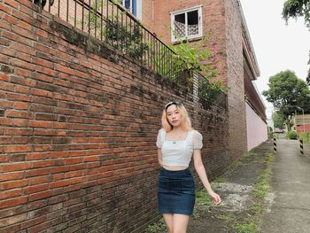 Portrait of woman standing against brick wall