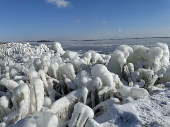 Snow on sea shore against sky