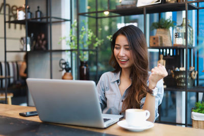 Young woman using phone while sitting on table