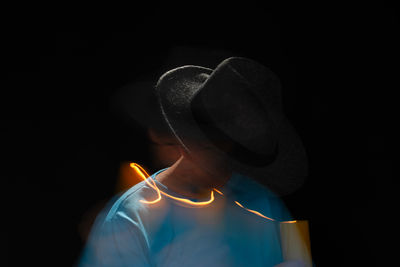 Portrait of bearded bald man in blue shirt wearing hat making light trail with burning candle