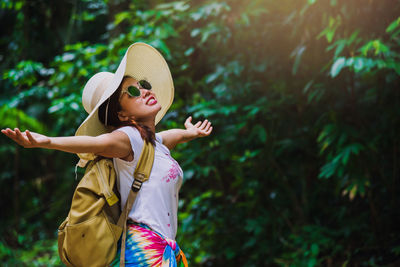 Full length of smiling woman standing against plants