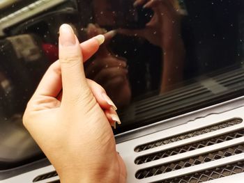 Cropped hand of woman gesturing by wet window