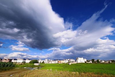 Houses on field against cloudy sky