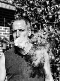 Portrait of man smoking against plants