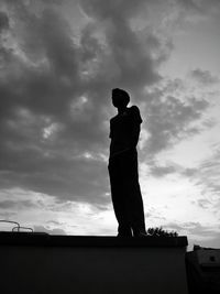 Low angle view of man standing on retaining wall against sky