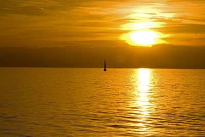 Scenic view of sail boat on lake geneva against orange sky at sunset