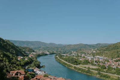 Scenic view of river and mountains against clear blue sky