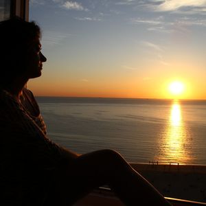 Man looking at sea against sky during sunset