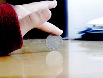 Close-up of hand holding coins on table
